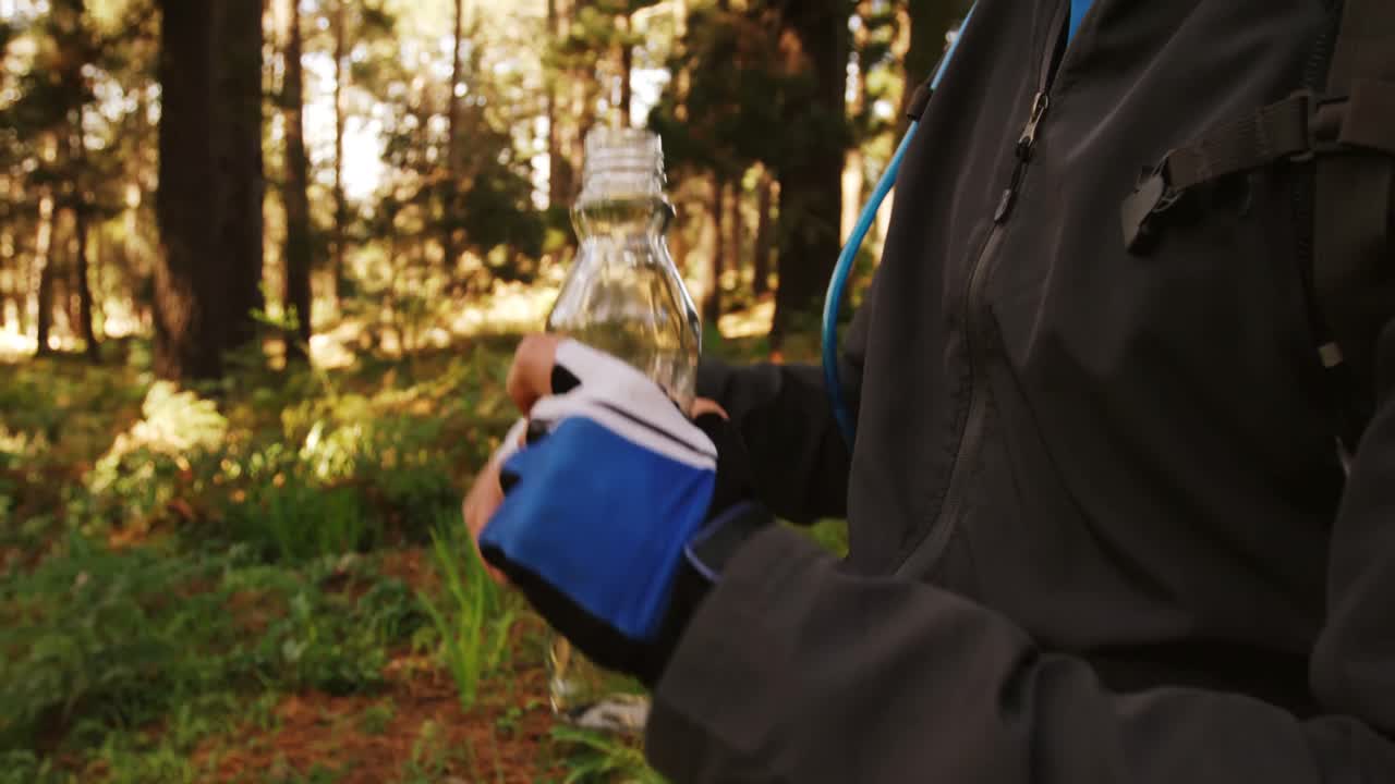 un ciclista de montaña bebiendo agua en el bosque