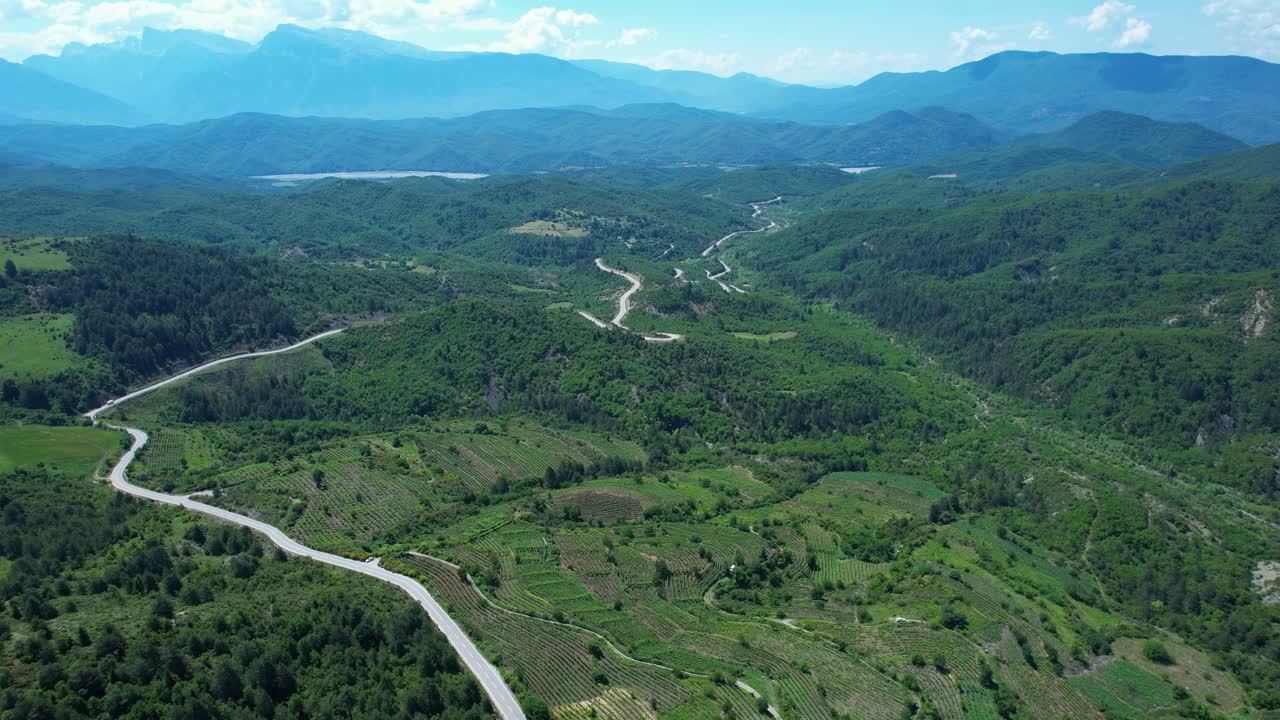 Road winding through vineyards and Mountains range green forest, Albania Greece border near scenic Leskovik