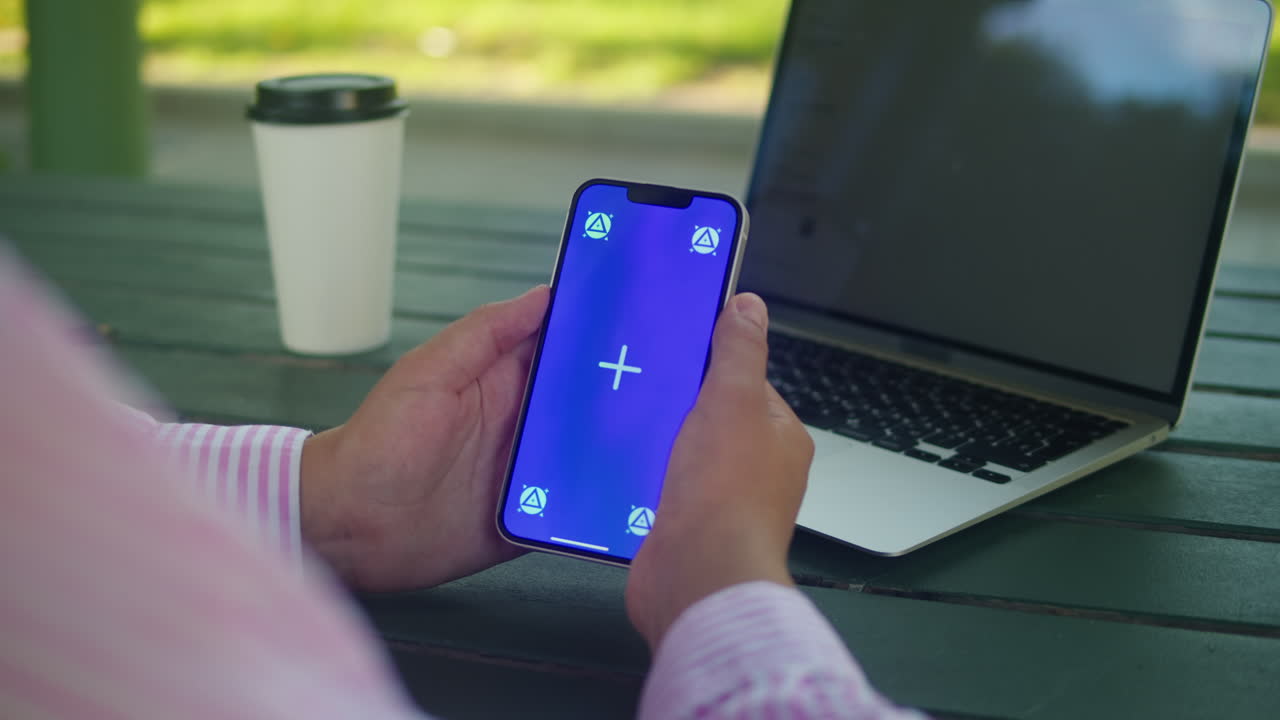 Woman hand holding phone with chroma key screen outdoor. Smartphone with green screen close-up