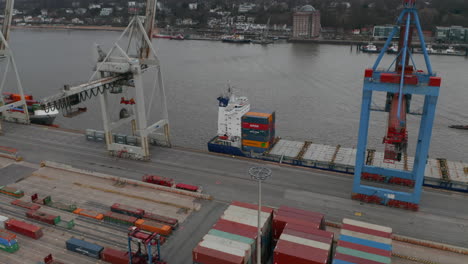 Aerial-dolly-view-of-cargo-ship-docked-in-the-commercial-cargo-port-in-Hamburg,-Germany