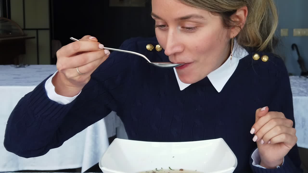 Close up of a woman eating chicken soup and smiling at a restaurant