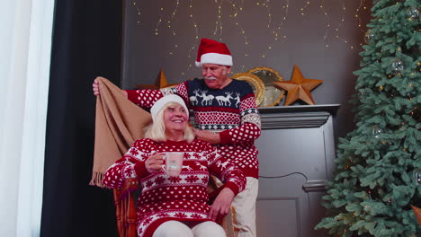 Senior-couple-celebrating-Christmas-grandfather-covers-with-a-blanket-grandmother-woman-drinking-tea