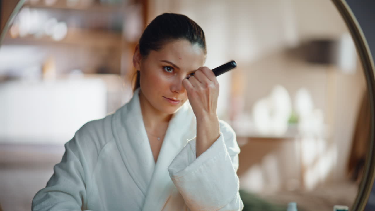 Smiling woman applying powder on healthy smooth face admiring reflection closeup