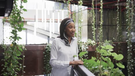 portrait of african american casual businesswoman standing in office foyer smiling, slow motion