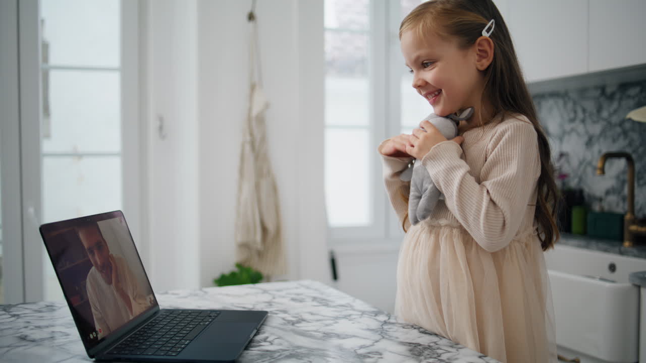 un niño encantador agitando una computadora portátil en la cocina de cerca. hija feliz hablando remotamente
