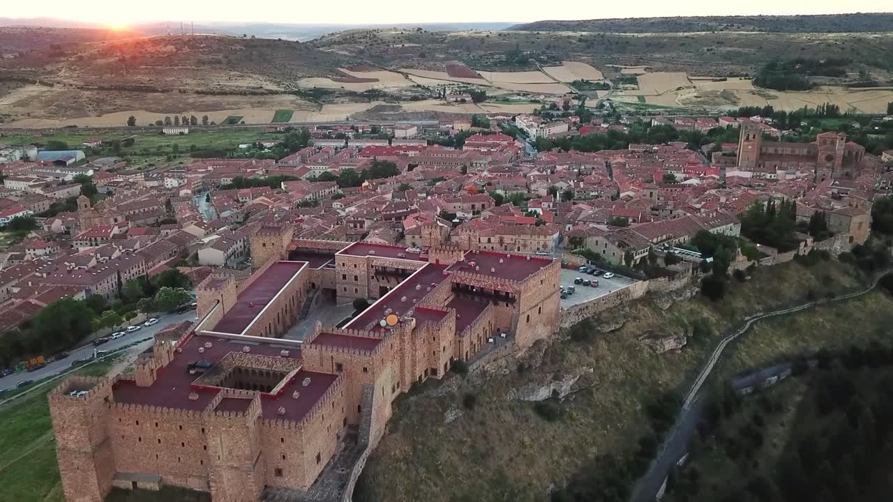 Vista aerea del Castello di Sigüenza, una magnifica fortezza medievale che domina la città di Sigüenza a Guadalajara, Castiglia-La Mancia, Spagna, immerso nel caldo bagliore del sole al tramonto.