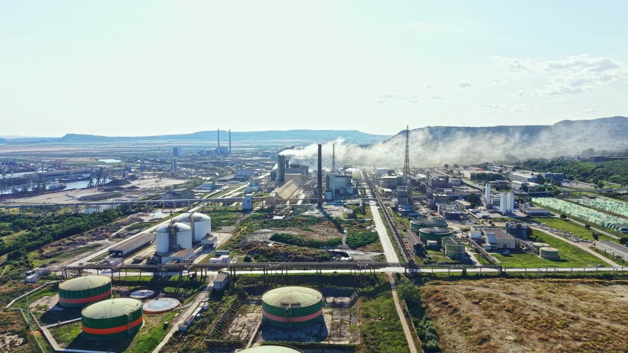 Factory site with large storage tanks and smoke from chimneys during daytime in an industrial area