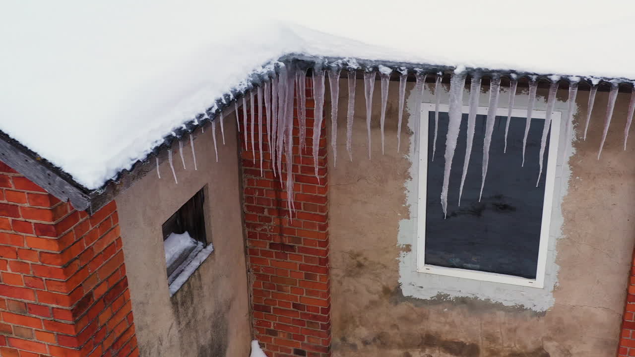 Dangerous icicles hanging from roof of an old abandoned warehouse, aerial truck left