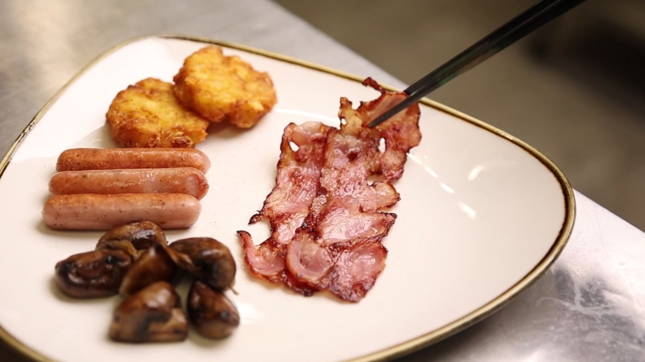 Bacchette che prendono pancetta croccante da un delizioso piatto per la colazione