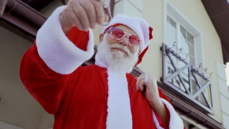 santa claus in pink glasses shake keys from a new house