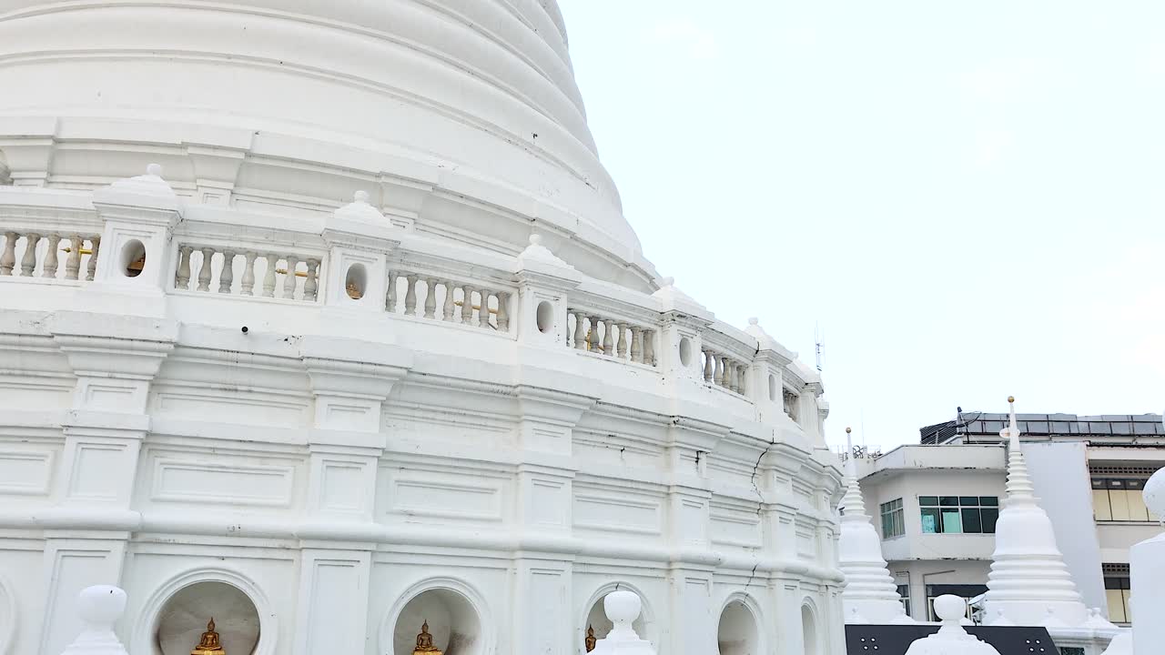 A serene aerial view of the white pagoda at Wat Prayurawongsawat in Bangkok, showcasing its intricate architecture against a clear sky
