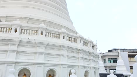 a serene aerial view of the white pagoda at wat prayurawongsawat in bangkok, showcasing its intricate architecture against a clear sky
