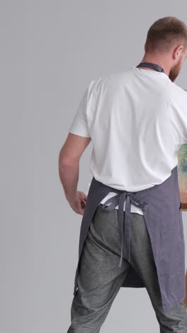 an artist in a work coat records a video blog as he paints a picture with brushes on a white canvas - an artist in a work coat records a video blog as he paints a picture with brushes on a white canvas. the process of creating an oil painting in the workshop