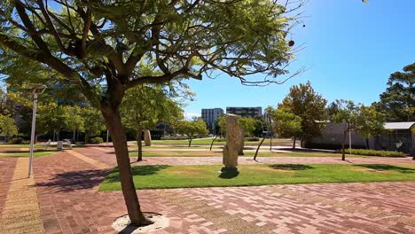 Walking-under-the-trees-and-landscaped-exterior-of-buildings-on-sunny-day