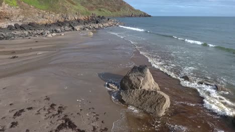 primer plano aéreo hacia adelante vista de la playa rocosa con olas estrelladas en porth ysgo en la península de illyn en gales en otoño