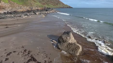 aerial closeup forwards view of rocky beach with crashing waves at porth ysgo on the llyn peninsula in wales in autumn