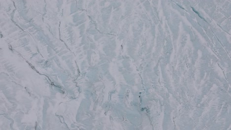 aerial top view of ice cracks and formations in virkisjokull glacier covered in snow, iceland