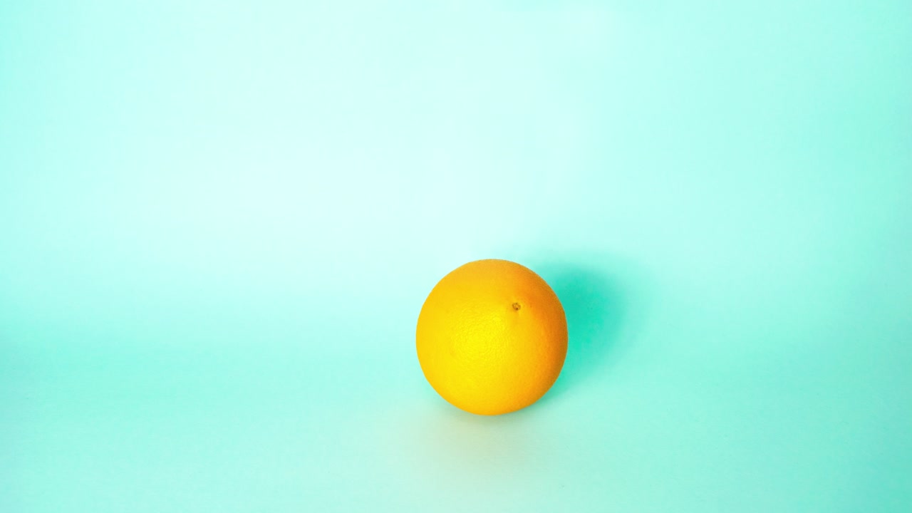 la fruta naranja salta de manera realista como una pelota, rebotando gradualmente más y más alto. aislada sobre un fondo azul.