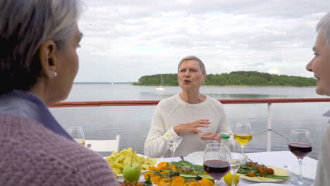 drei ältere frauen beim abendessen und getränken im freien