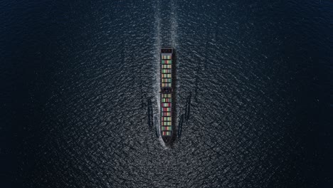aerial view of a large cargo ship moving through dark water