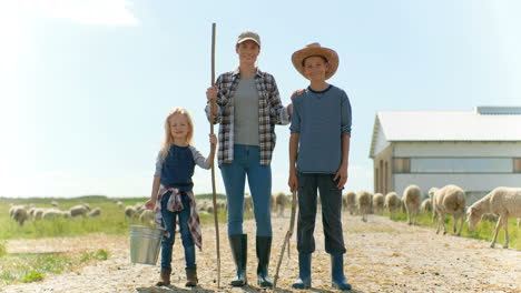 portrait of happy caucasian mother standing in field with small son and daughter