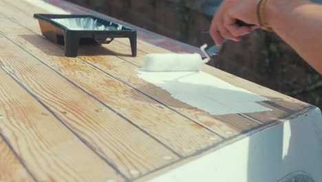 applying white primer paint on wooden planks of wood boat wheelhouse cabin