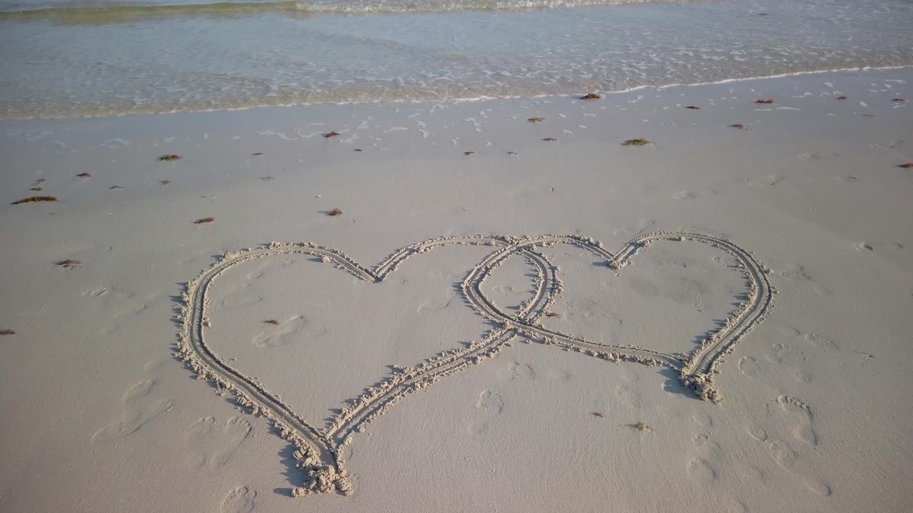 해변에서 찰싹 때리는 물과 함께 해변에 있는 두 개의 연동 하트의 정적 샷