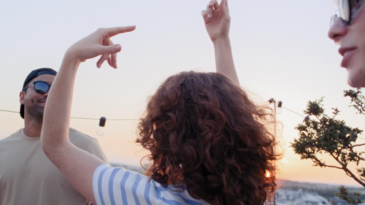 다민족 친구들이 지붕 위의 파티에서 춤을 추고 있습니다.