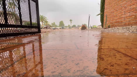 Gotas-De-Agua-Sobre-Ladrillo-Rojo-Frente-A-Una-Casa,-Cámara-Cerca-De-La-Superficie