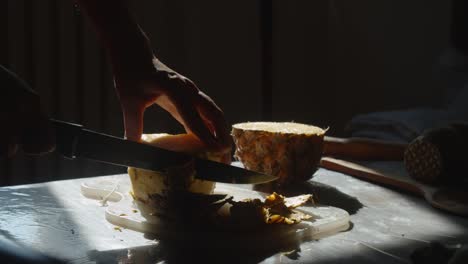 manos pelando piña, primer plano, cámara lenta
