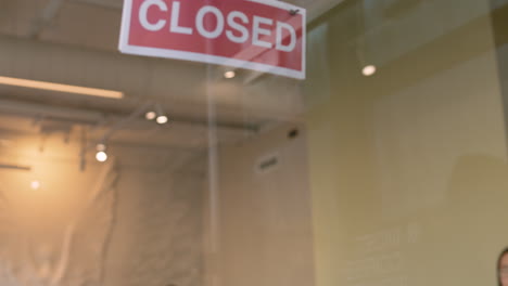 waiter putting an open sign on the coffee shop door