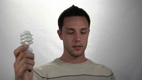 a man holds a compact-fluorescent light bulb in one hand and money in the other