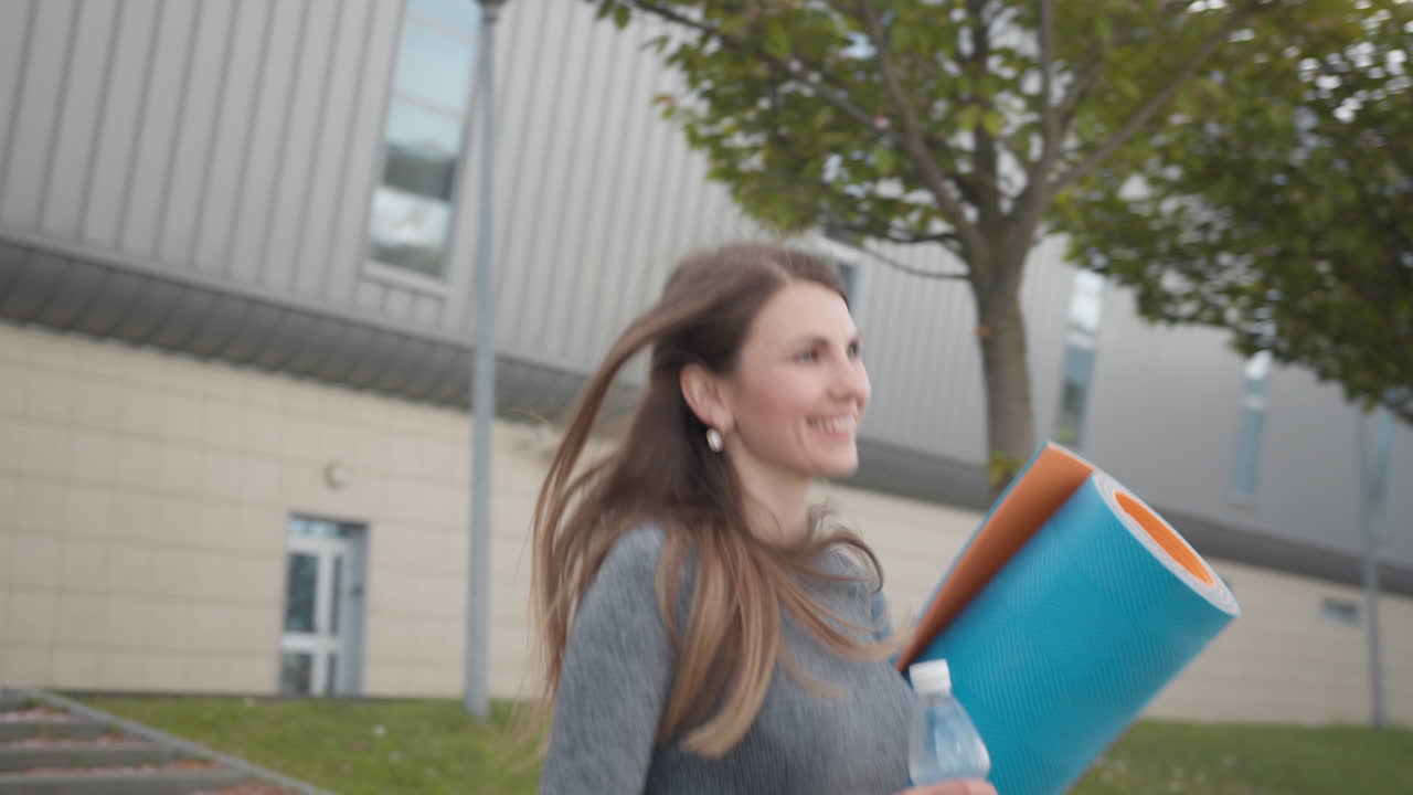 Žena cvičí venku s jógamatkou a lahví na vodu
