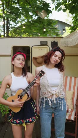 two women playing ukulele outdoors