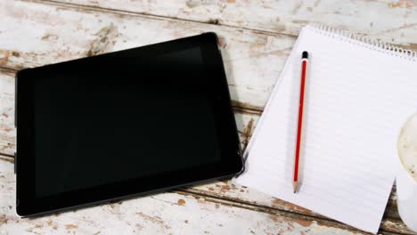 tableta digital, bloc de notas, taza de café y teclado