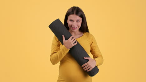 pregnant woman holding yoga mat
