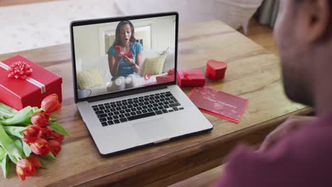 Feliz-Mujer-Afroamericana-Abriendo-Un-Regalo-Y-Haciendo-Una-Videollamada-Del-Día-De-San-Valentín-En-Una-Computadora-Portátil