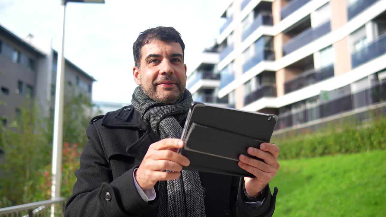 Man outdoors using a tablet and looking up