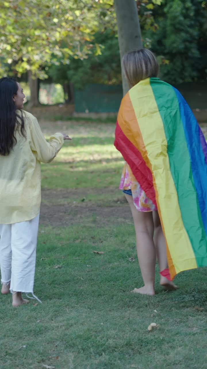 Lesbian couple with rainbow flag in park