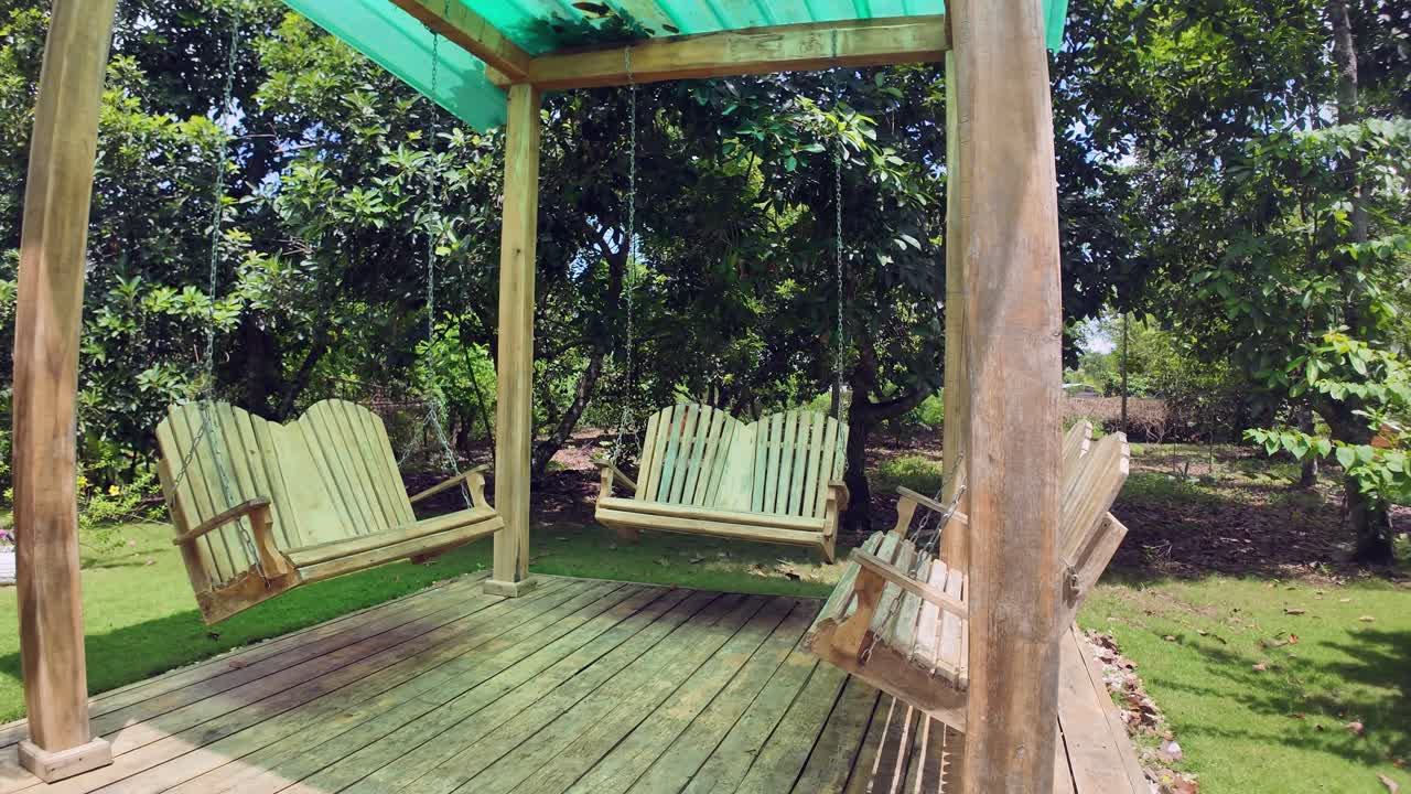 Swing chairs attached by chains to a simple house. Calm and Relaxed Atmosphere in the backyard.