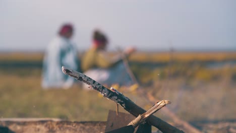 burning bonfire against blurred lesbian couple on bank