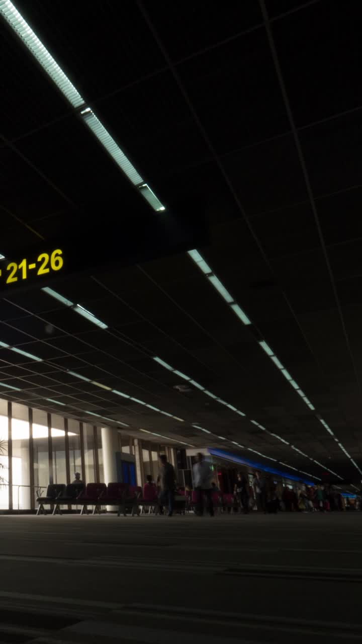 Viajeros caminando por un oscuro pasillo de terminal de aeropuerto