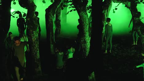 artistic performance in an eerie green forest with dancers