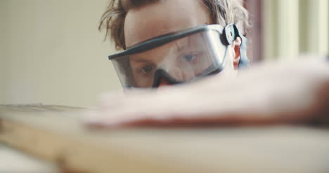 carpenter in protective glasses checking wooden board