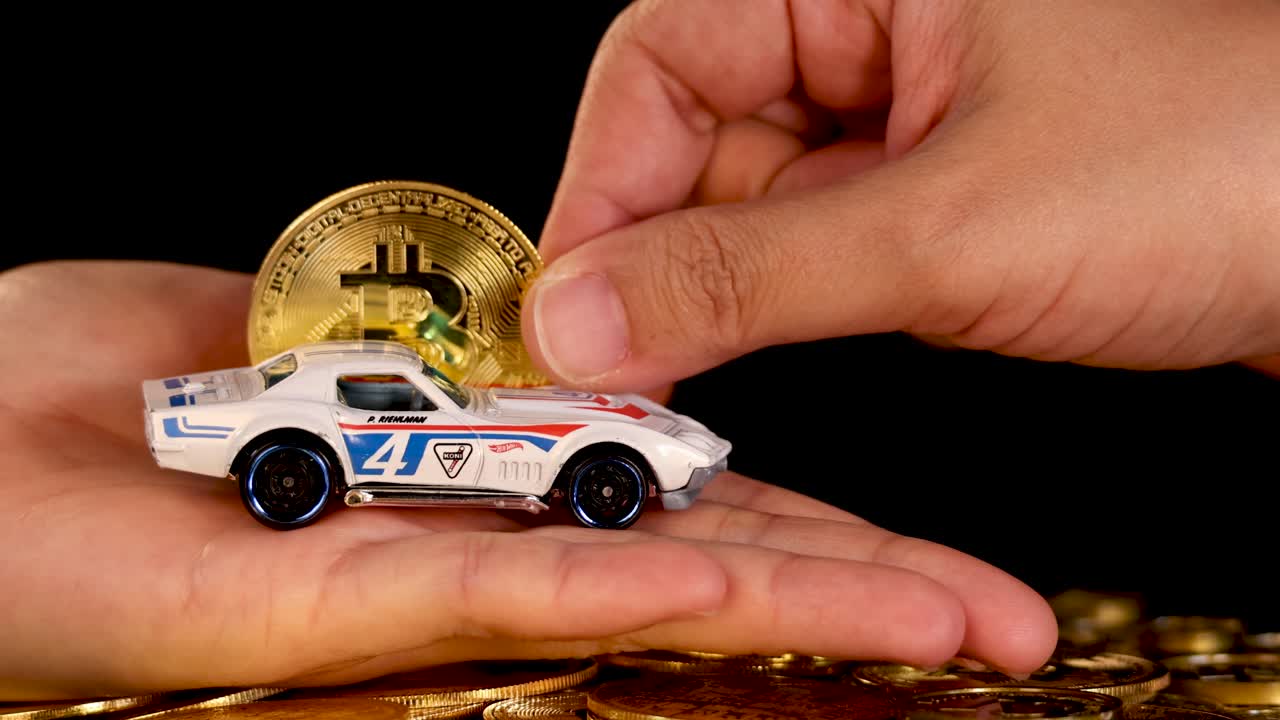 Hand trades toy car for gold Bitcoin coin, close-up, dramatic lighting, black background, smooth motion