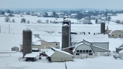 snow blankets a farm with silos and barns amidst a rural pennsylvanian landscape