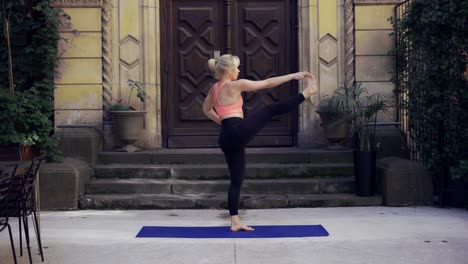 Frau-Macht-Yoga-über-Der-Veranda-Mit-Großer-Holztür