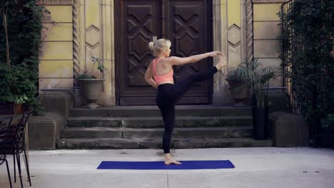 mujer haciendo yoga sobre el porche con una gran puerta de madera
