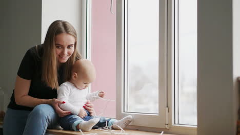 Mutter-Und-Ihr-Kleiner-Sohn-Haben-Spaß-Und-Spielen-Zu-Hause.-Kleines-Kind-Im-Alter-Von-1-Jahr-Spielt-Mit-Den-Armen-Seiner-Mutter-Zu-Hause-In-Der-Nähe-Eines-Großen-Fensters