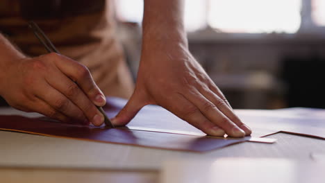 Professional-worker-cuts-leather-material-at-workbench